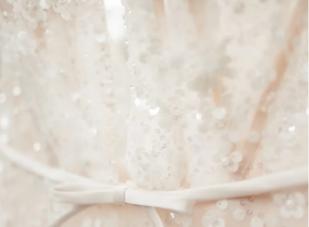 Close detail of a white wedding dress and ribbon