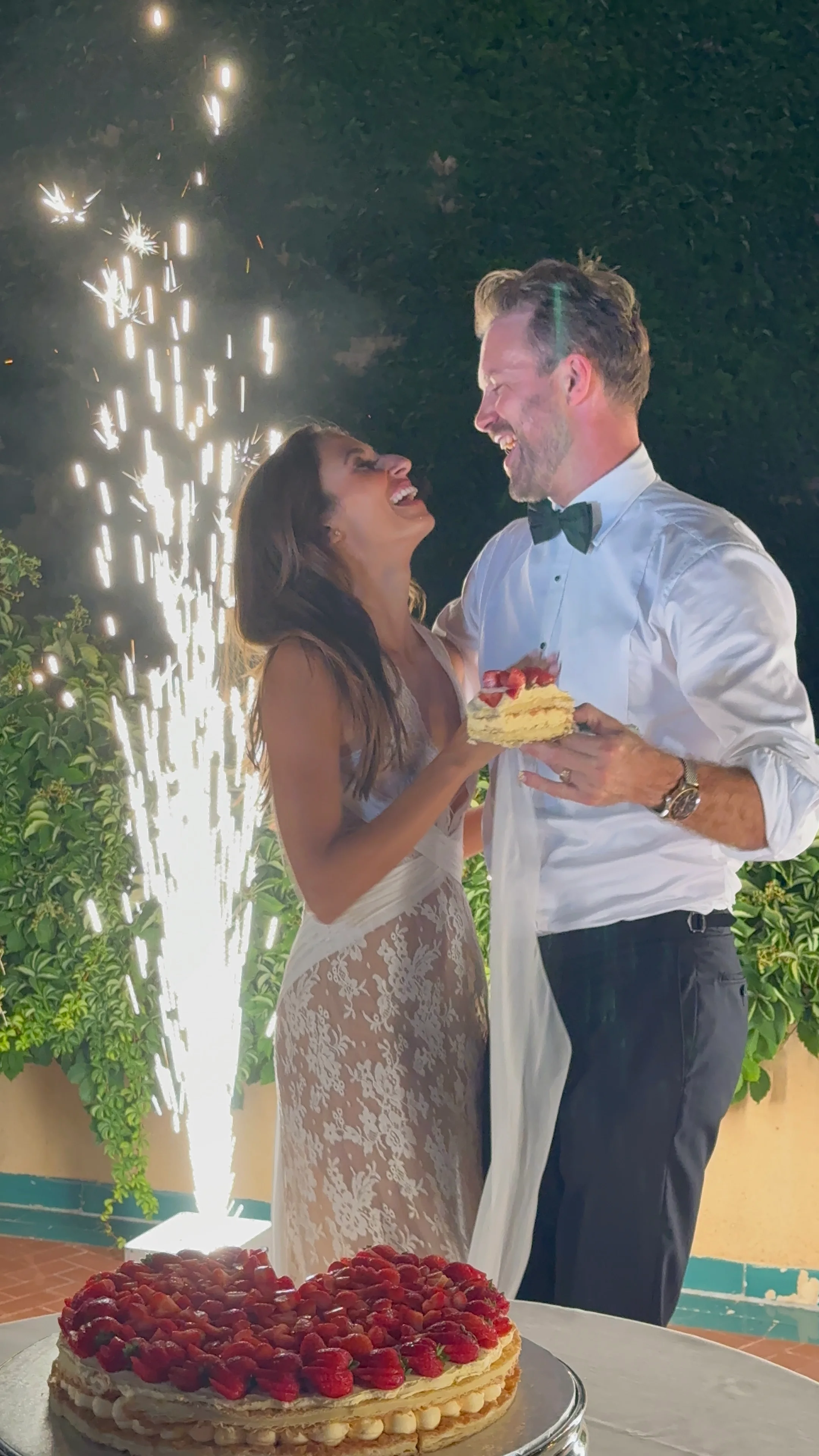 Bride and groom beside sparklers at night