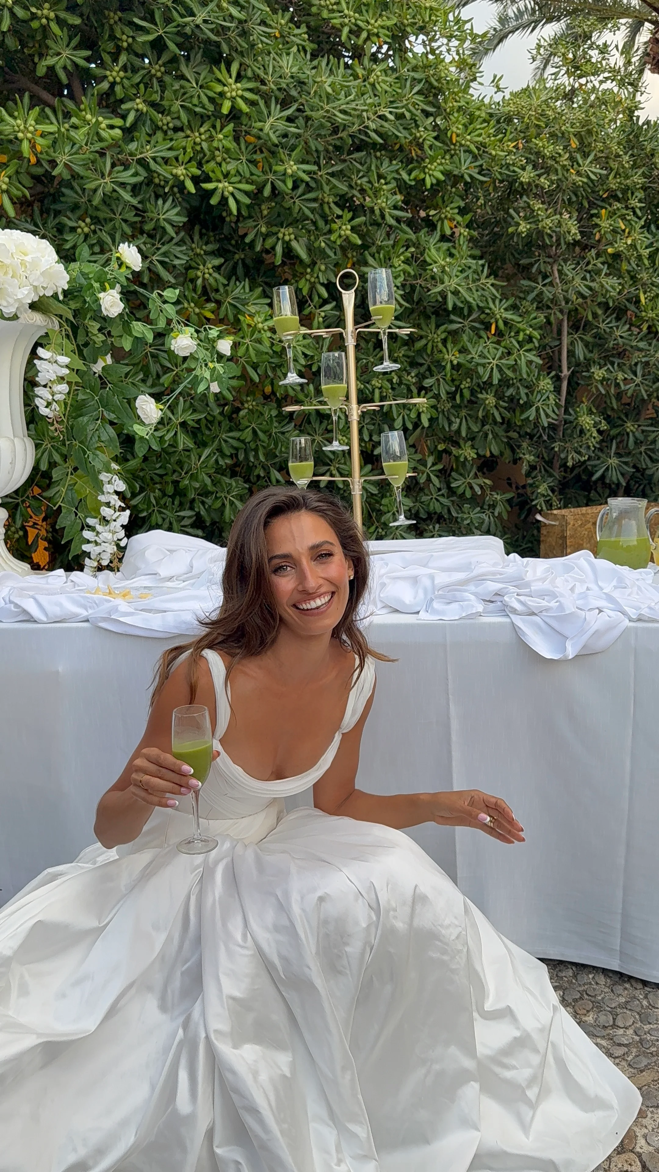 Bride seated outdoors beneath greenery
