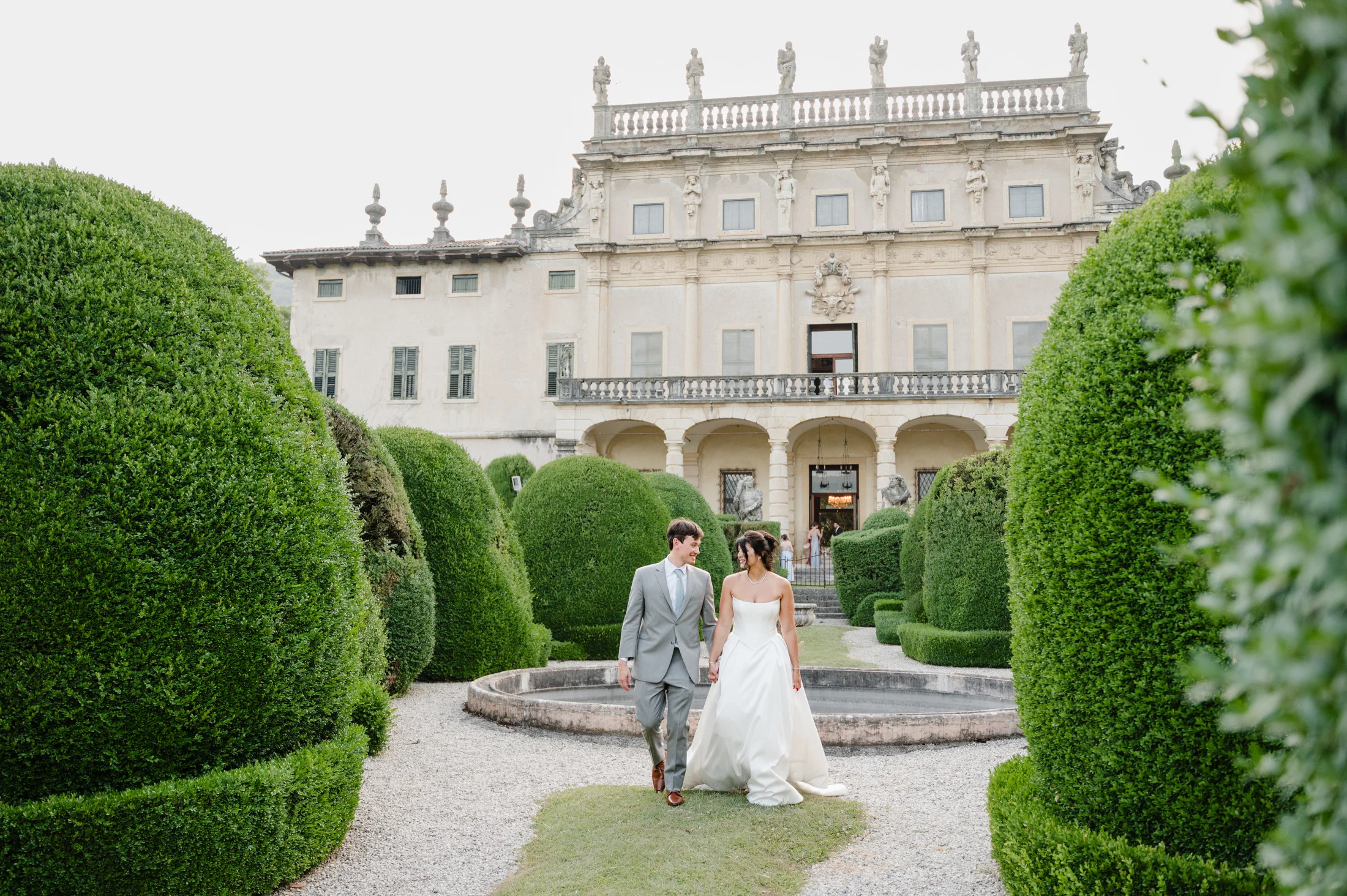 Bride and groom approaching a villa through the gardens