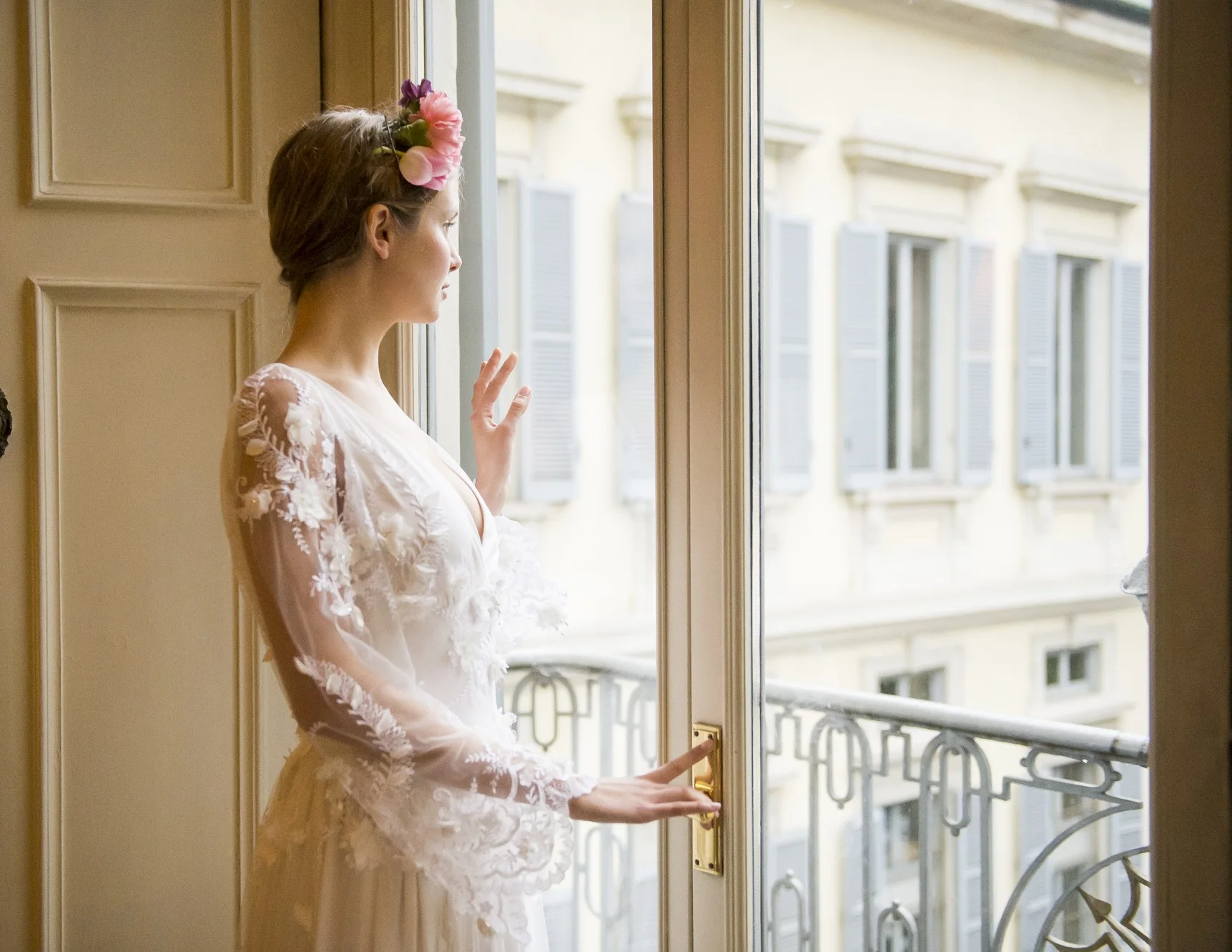 Bride standing beside a tall open window