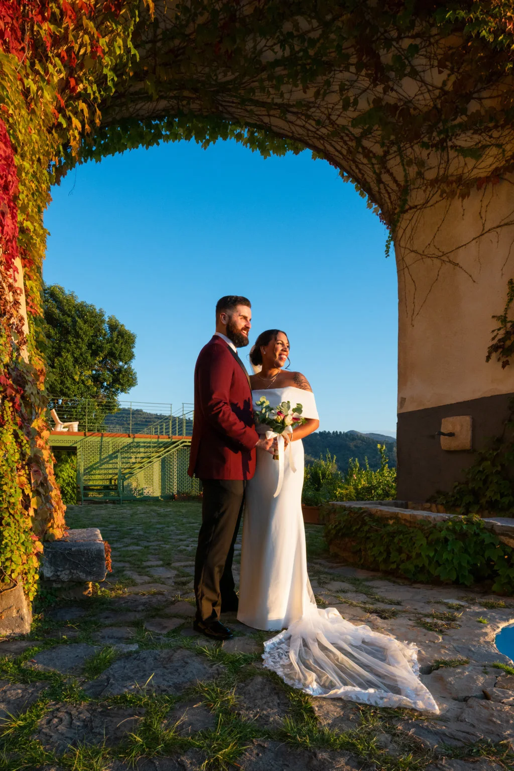 Bride and groom beneath a stone arch