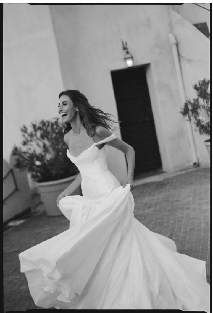 Black-and-white photograph of a bride with her dress spread around her