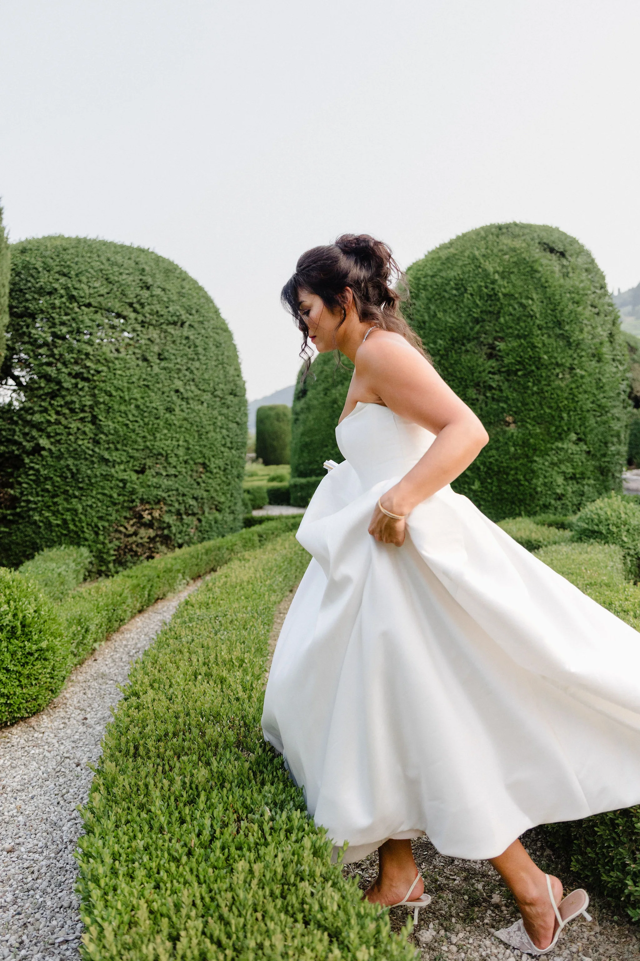 Bride walking among sculpted garden hedges