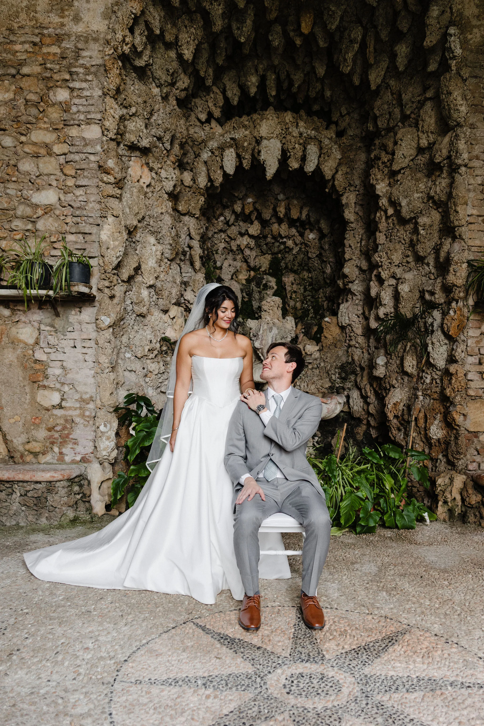 Bride and groom standing beneath a stone arch