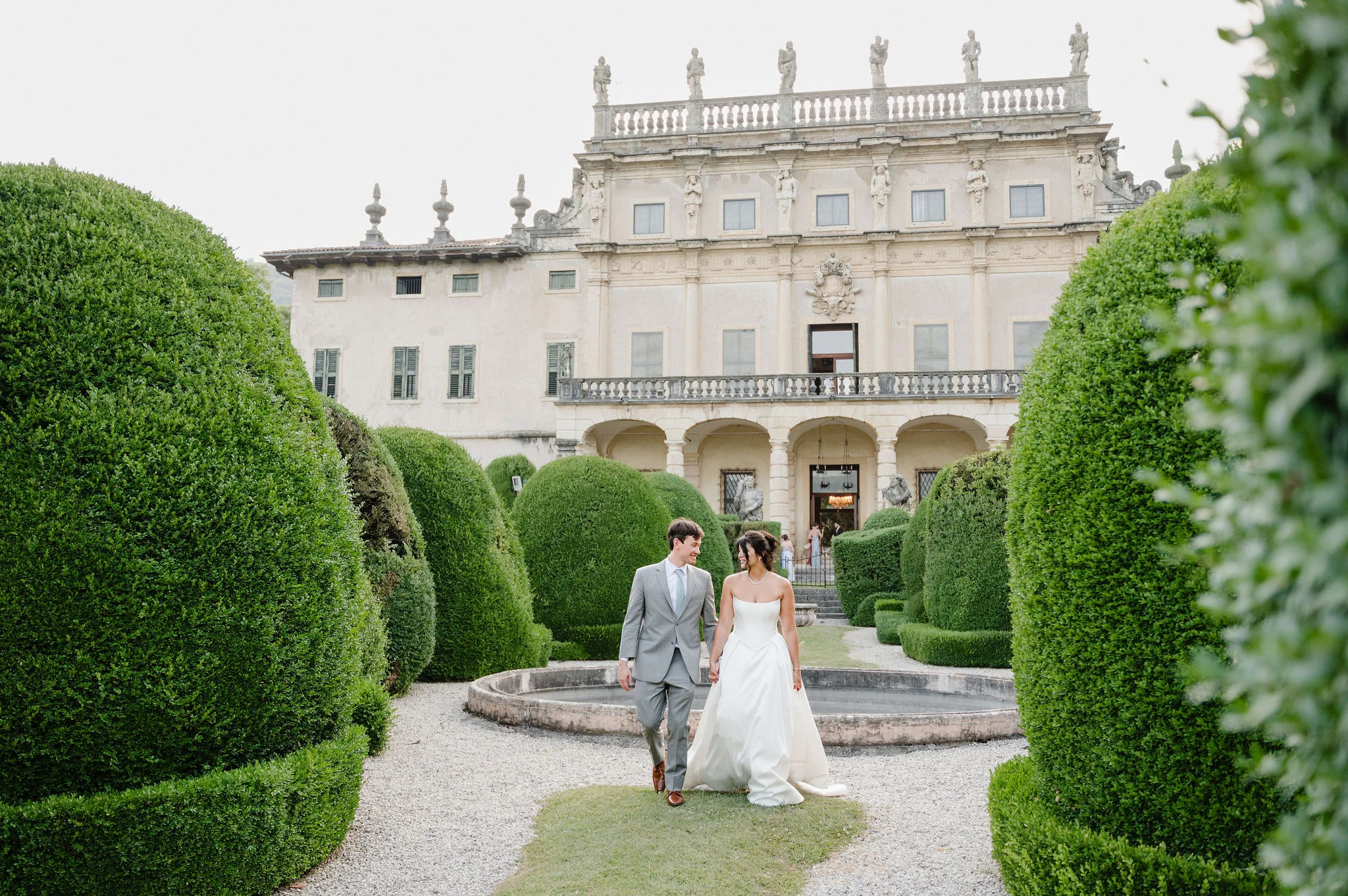 Bride and groom walking through a villa garden