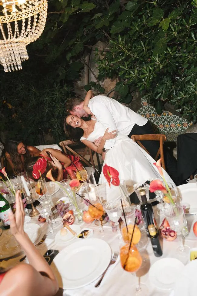 Bride and groom kissing beside their reception table