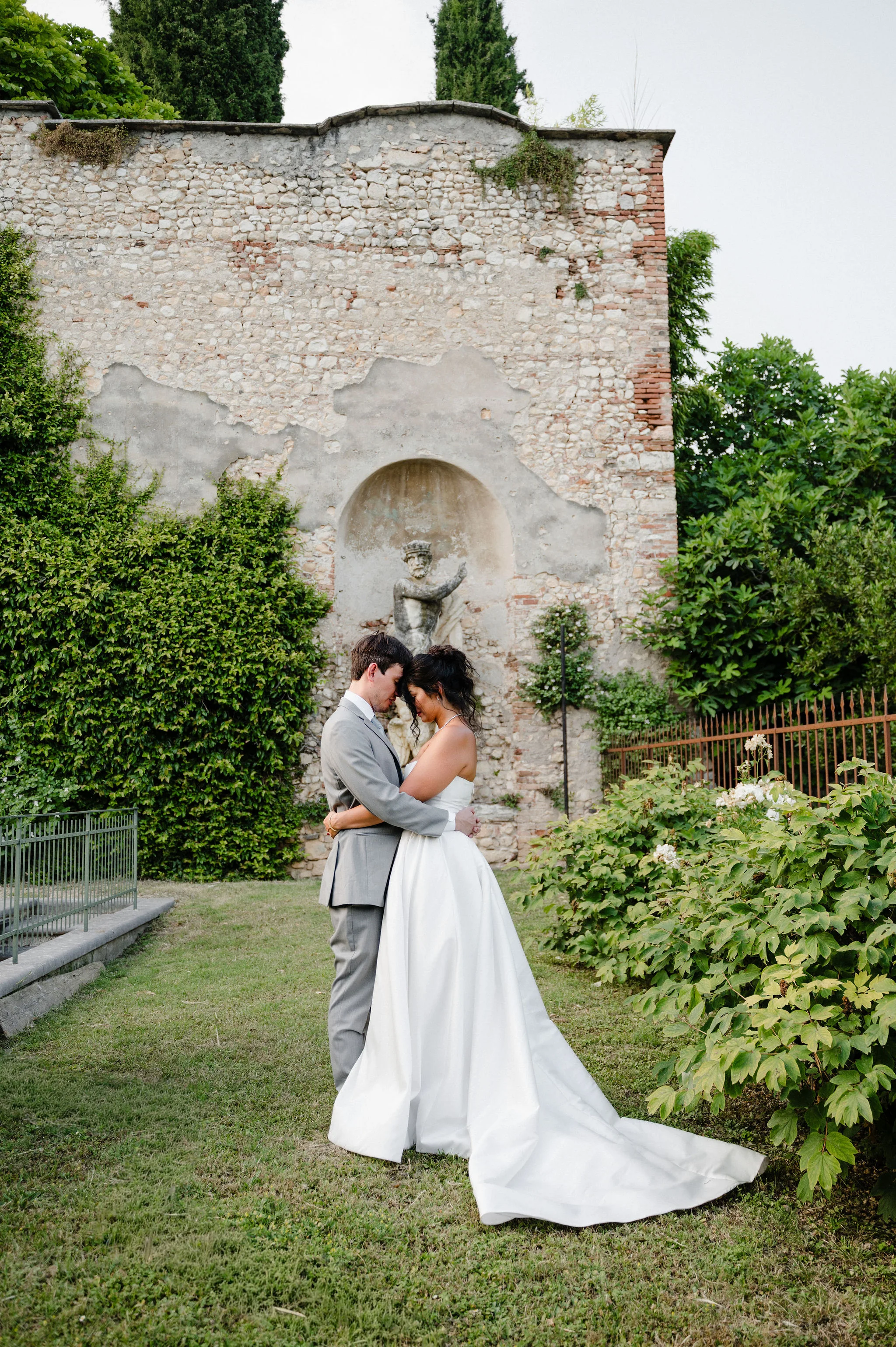 Bride and groom by a garden wall