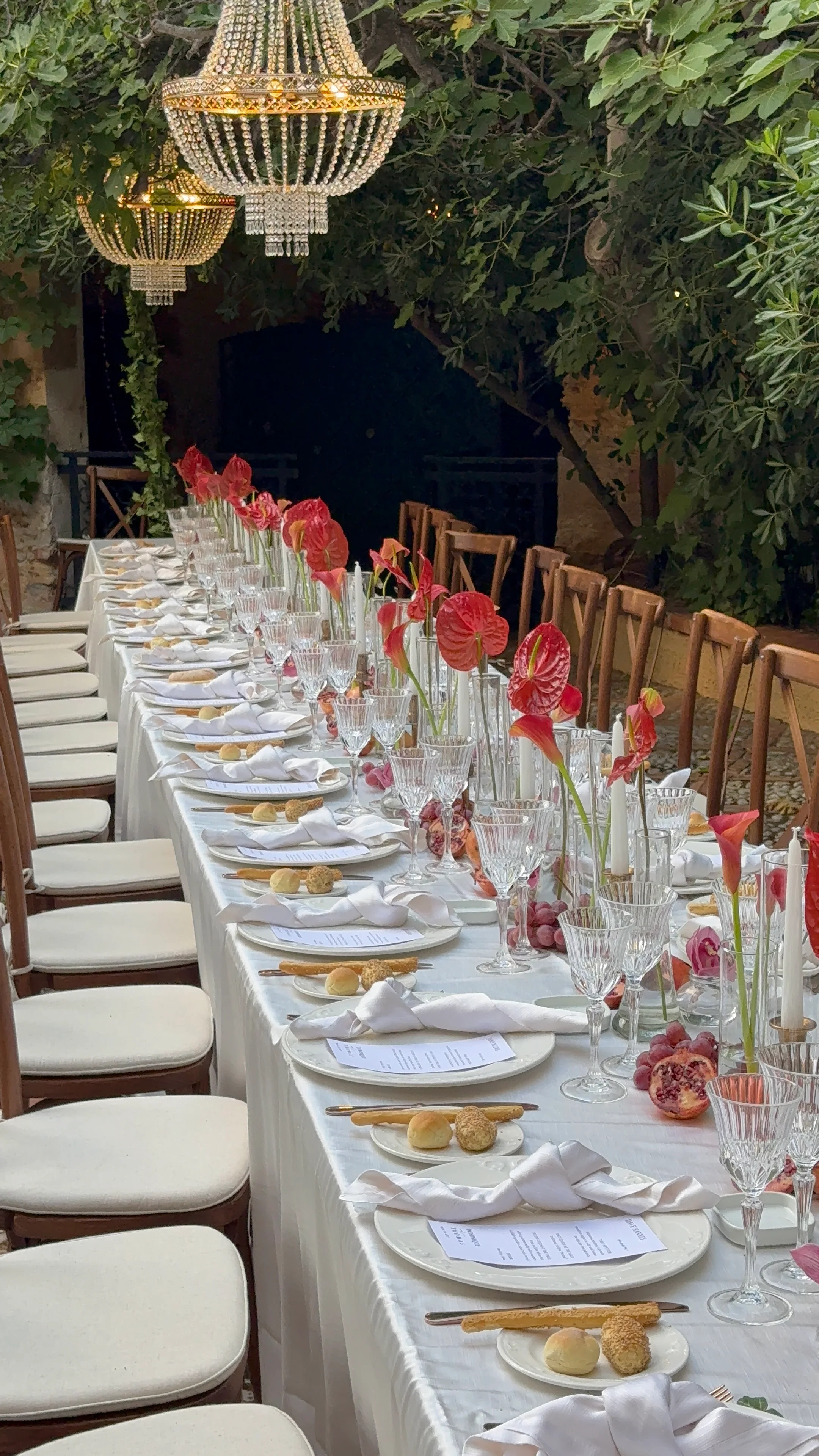 Long candlelit reception table beneath greenery