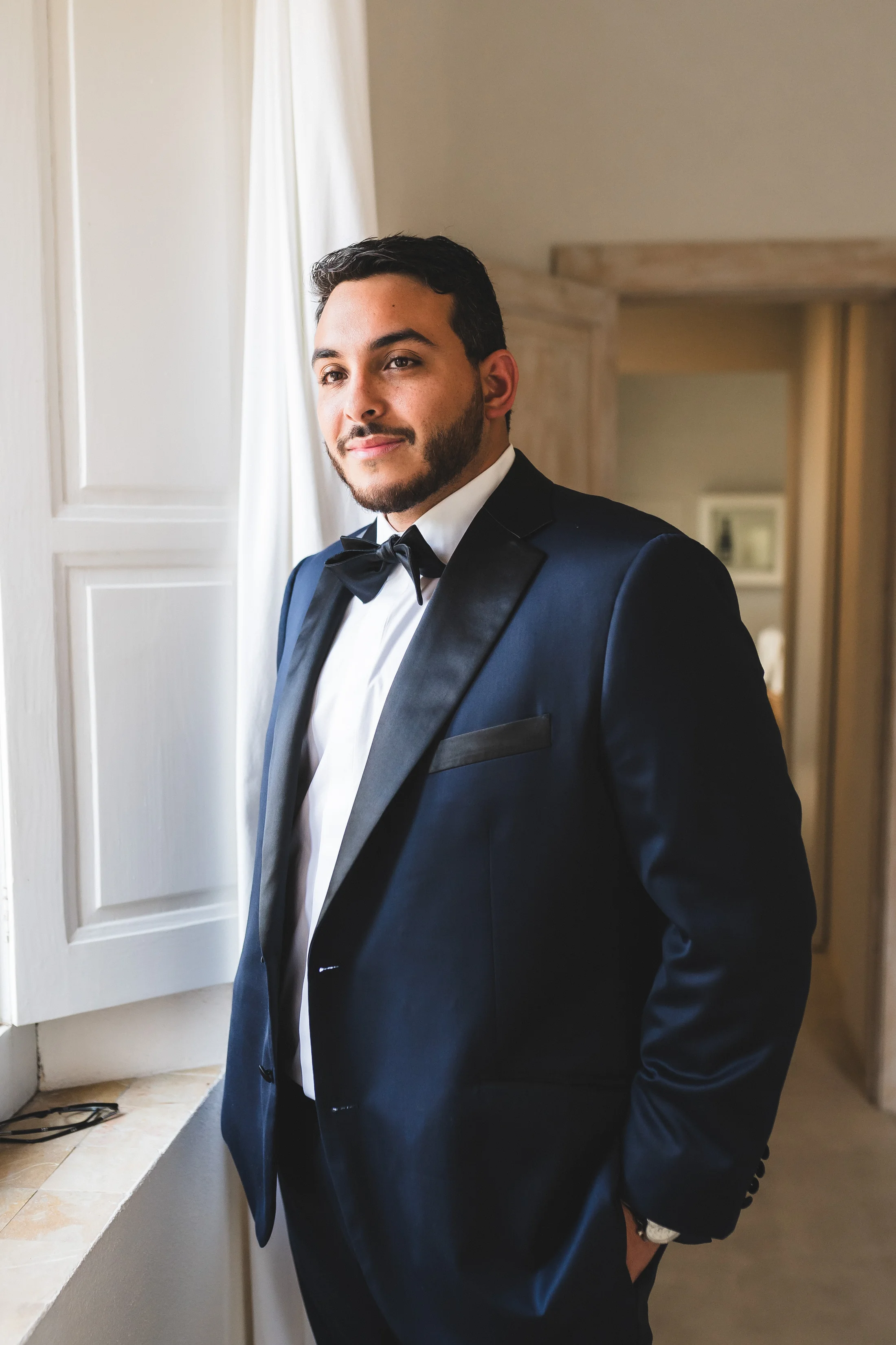 Groom standing beside an open window