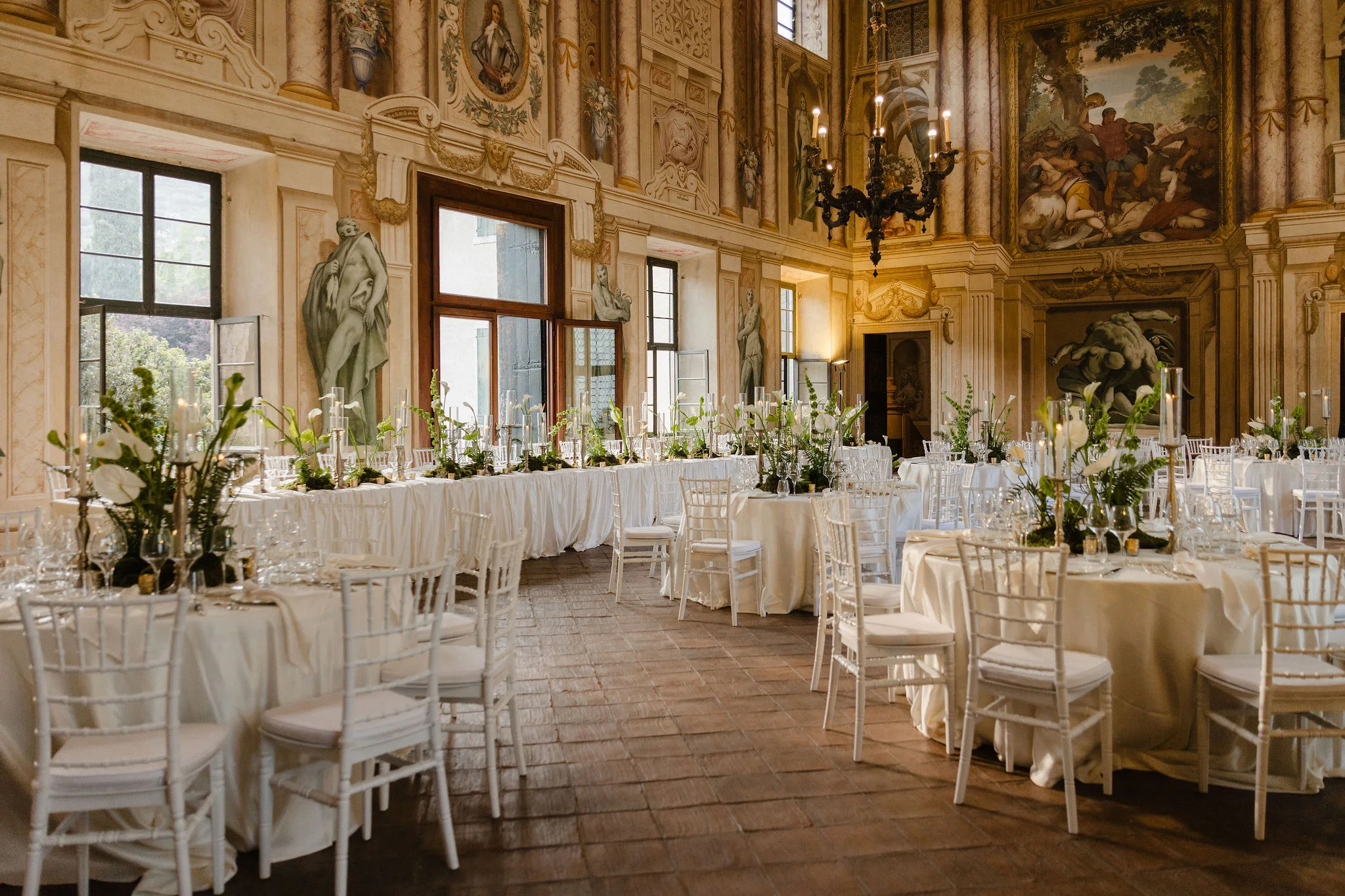 Reception tables in a gilded room with chandeliers