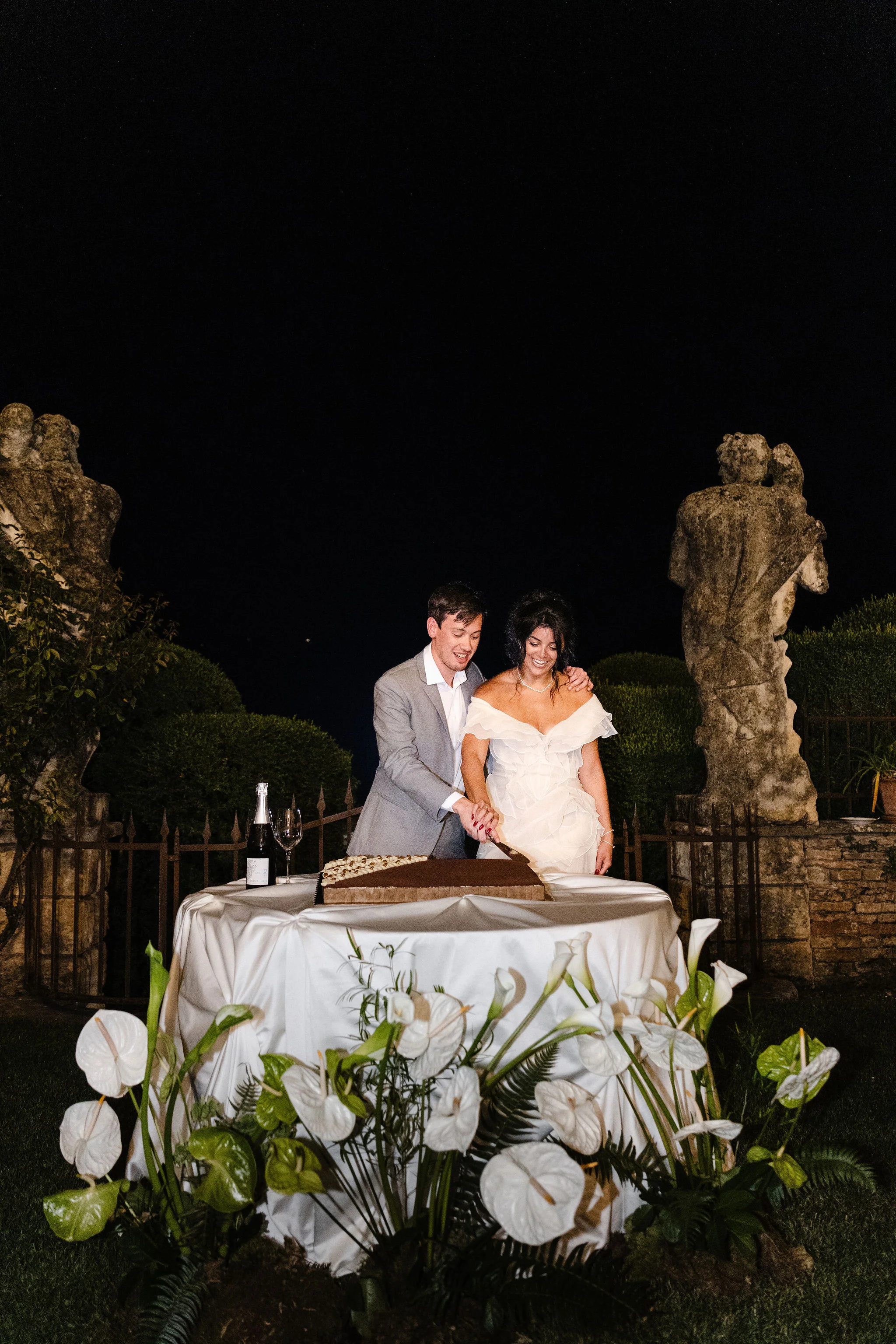 Bride and groom cutting their wedding cake at night