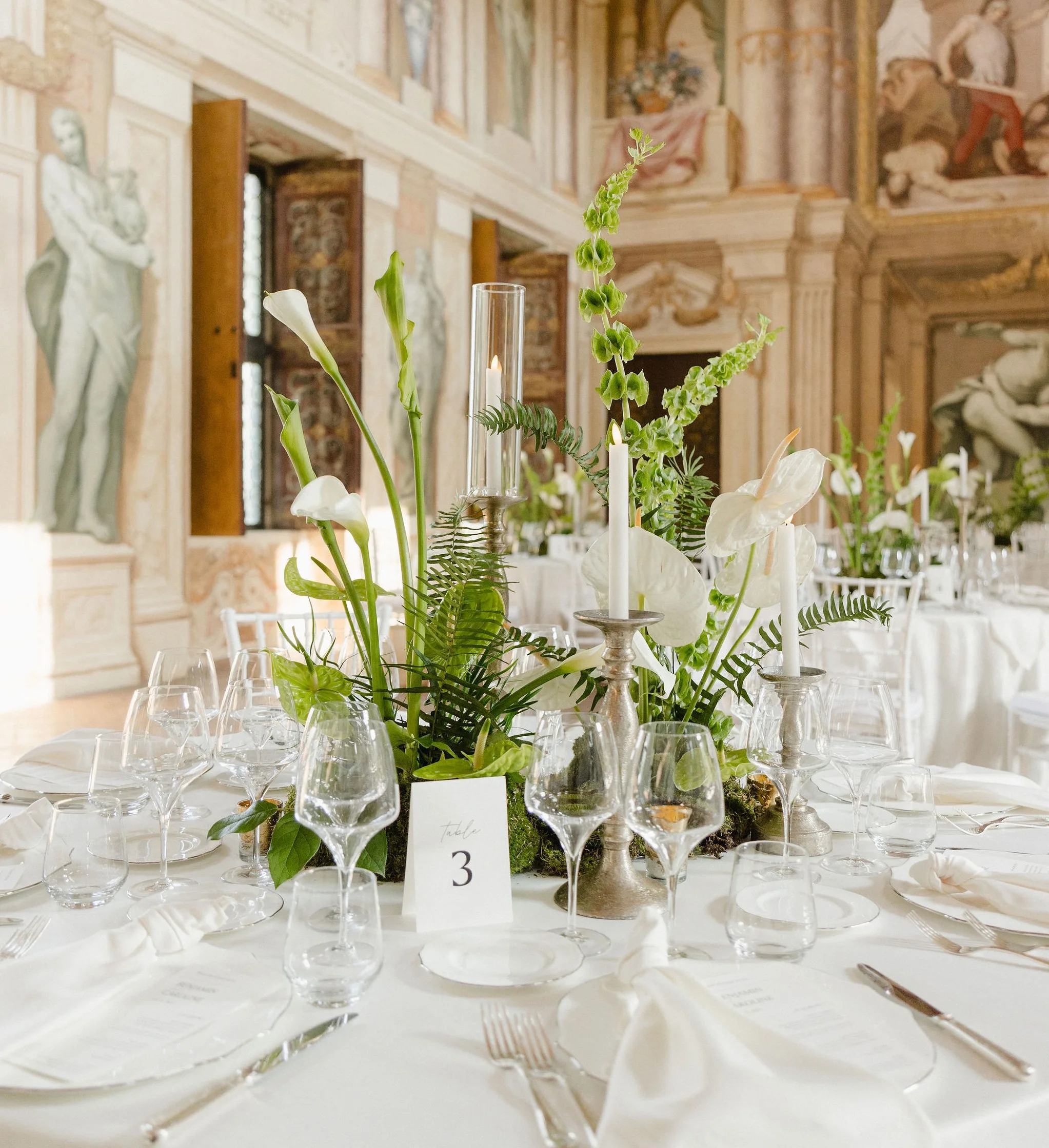 Reception table beneath gilded chandeliers