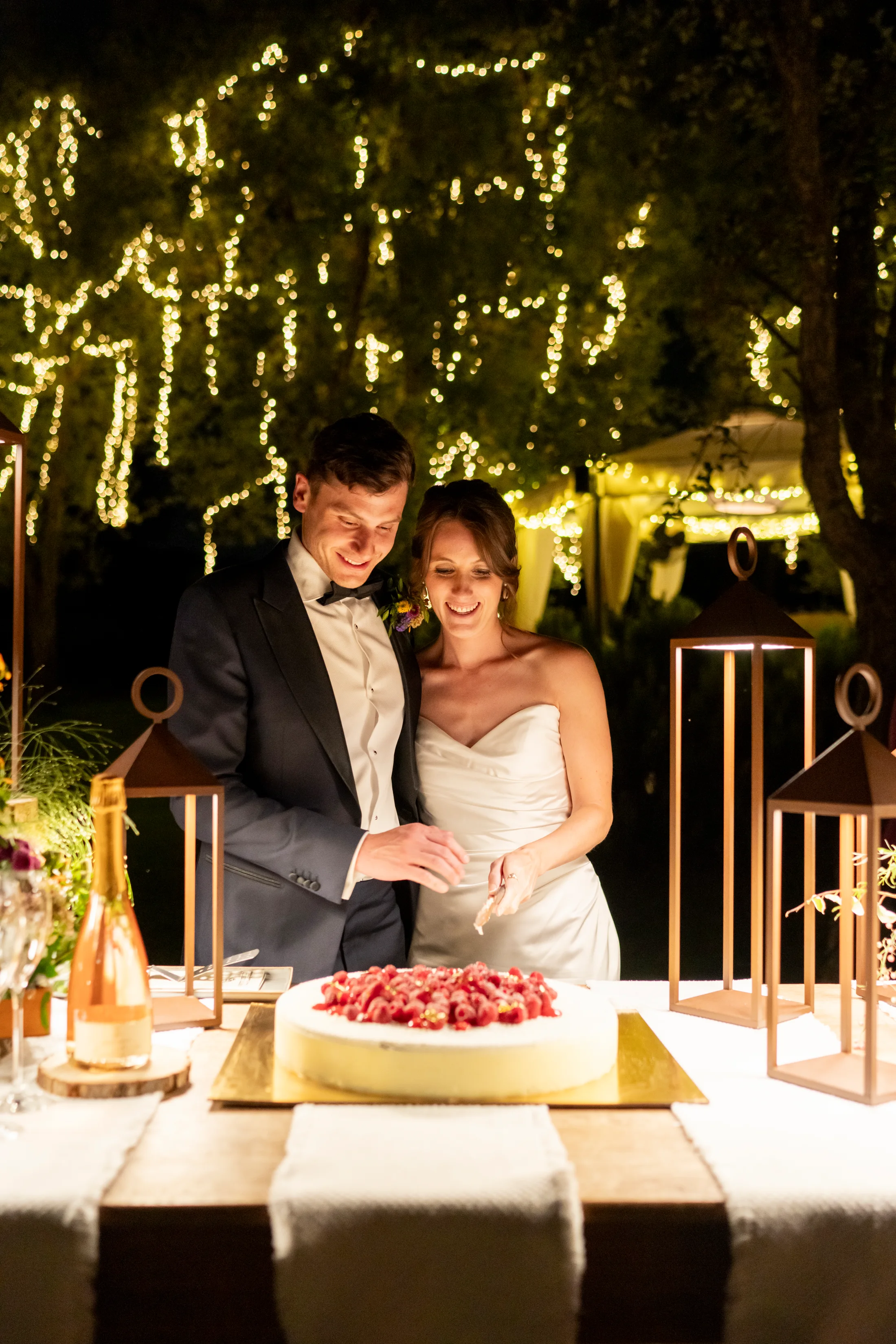 Bride and groom cutting a berry-topped cake