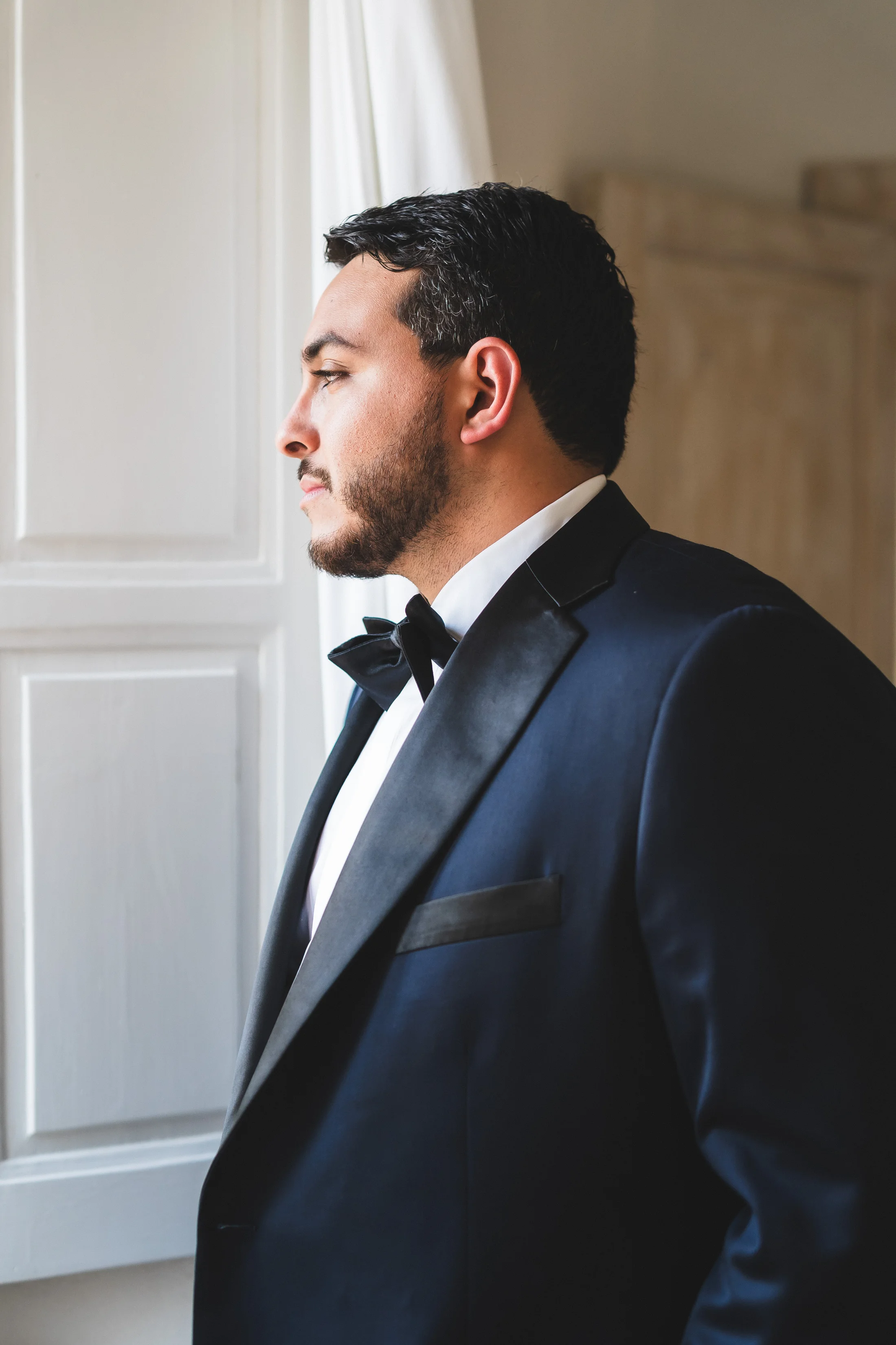 Portrait of a groom beside a window