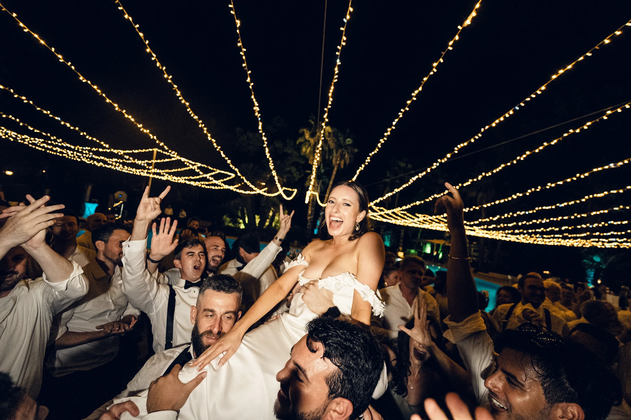Guests celebrating beneath strings of lights