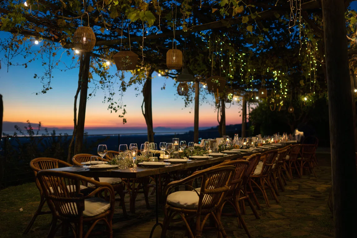 Reception tables beneath a pergola at sunset