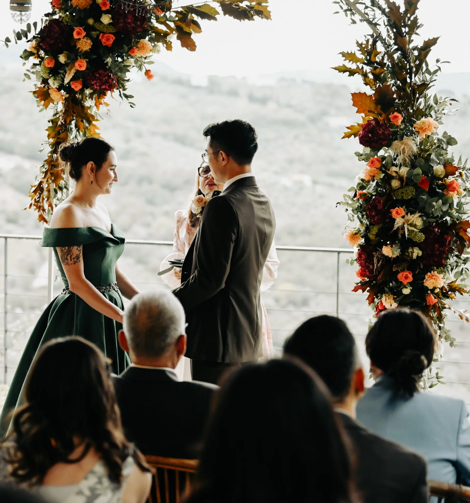 Outdoor wedding ceremony beneath a floral arch