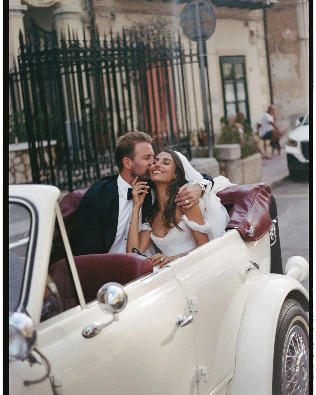 Bride and groom riding in an open-top car