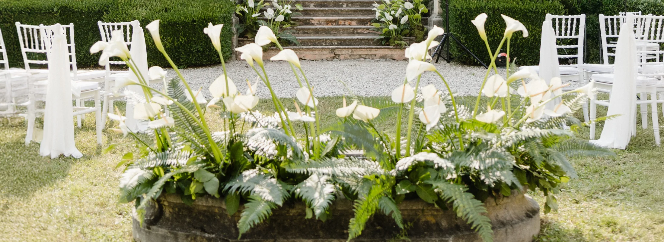 White flower arrangement beside outdoor ceremony chairs