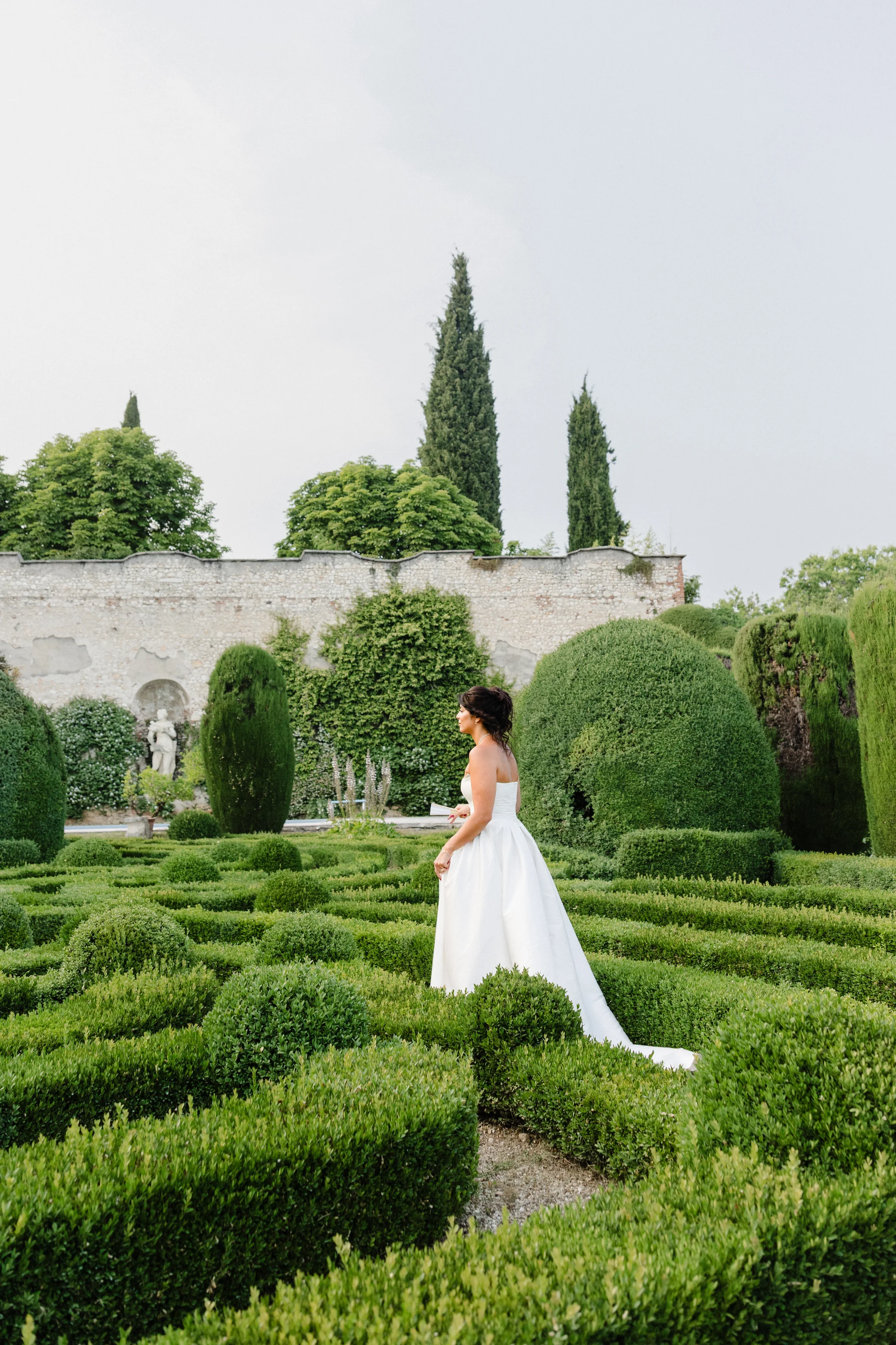 Bride among sculpted hedges in a formal garden